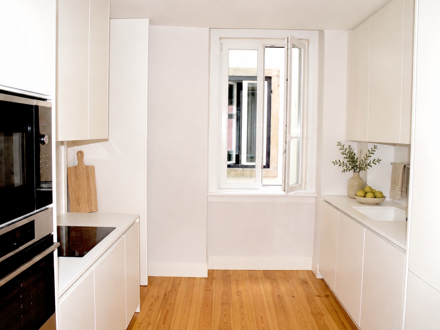 Cozinha equipada em branco com bancada contínua e janela aberta