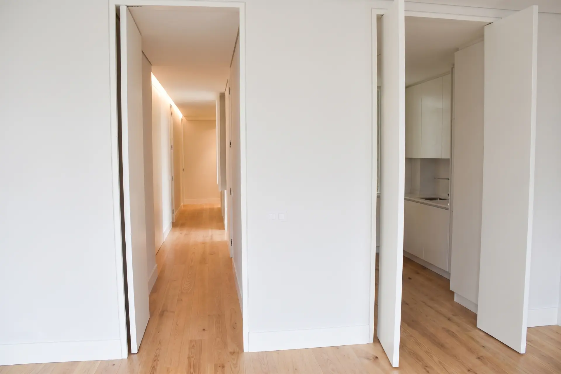 Corredor com acesso à cozinha e às áreas privadas do apartamento